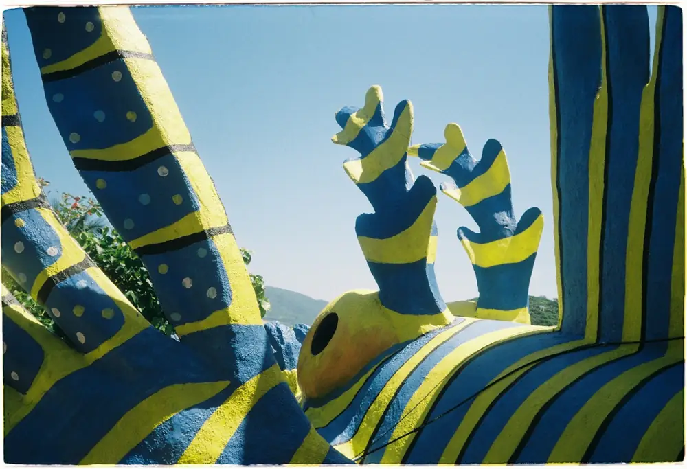 Escultura abstrata ao ar livre pintada com faixas azuis e amarelas.
