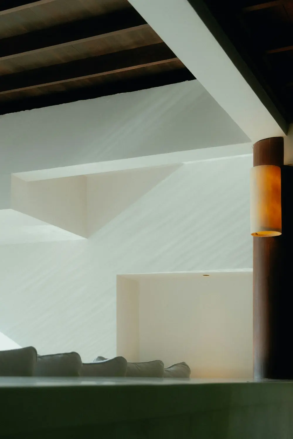 Interior minimalista com paredes claras, estrutura de madeira e iluminação indireta.